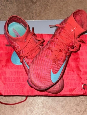 Nike Mercurial superfly 10 elite fg mad energy  - Pris kan diskuteras. Snygga Nike Mercurial superfly 10 elite fotbollsskor i starkt rosa med turkosa detaljer och logga. Skorna har strumpliknande skaft, snörning och en lätt, slitstark ovandel i syntetmaterial. Sulan har dobbar för bra grepp på planen. Perfekta för dig som vill sticka ut på matchen.