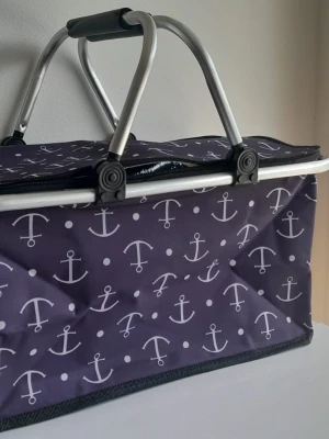 Stor isolerad picknickkorg - 30L kylväska med retromotiv och blommönster - Denna bärbara kylväska på 30 liter är perfekt för familjeutflykter, stranddagar eller matinköp. Den har ett fantastiskt retroblommigt 70-talstryck i varma hösttoner (orange, gult och brunt).  Viktiga funktioner: Stor kapacitet: 30 liter (gott om plats för drycker, snacks och lunch). Isolerad insida: Håller mat och dryck svala eller varma i timmar.  Robust design: Lätt aluminiumram med ett bekvämt vadderat handtag. Mått: 40 cm x 23 cm x 30 cm (ca 15,7" x 9,05" x 11,8").