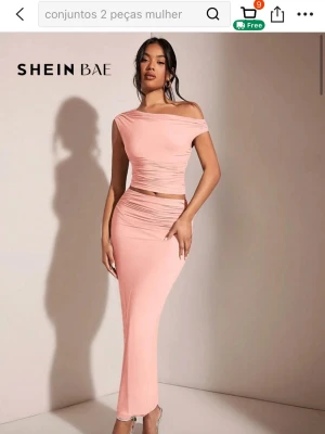 Rosa set från SHEIN BAE - Trendig långkjol i ljusrosa från SHEIN BAE. Kjolen har en tight passform och är gjord i ett mjukt, stretchigt material. Snygga rynkade detaljer längs sidorna ger en modern look. Matchande top till