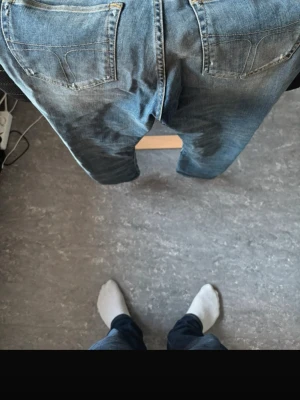 Tiger of Sweden  - Säljer ett par klassiska blå jeans med snygga slitningar och tvättade detaljer. Jeansen har fem fickor och raka ben. Perfekta för en avslappnad och trendig stil. Materialet är denim i bomull.  Helt nya utan pris lapp 