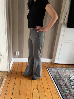 Gråa vida kostymbyxor - Snygga grå kostymbyxor med utsvängda ben och klassisk passform. Perfekta för en stilren look. Medelhög midja
