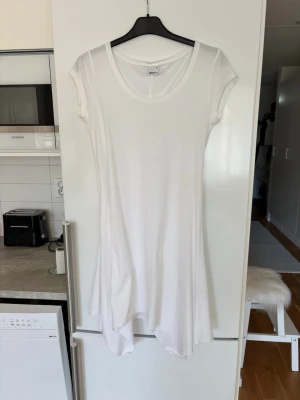 Vit asymmetrisk klänning från Only - Säljer en enkel och stilren vit klänning.Klänningen har korta ärmar, rund halsringning och en asymmetrisk nederkant som ger en cool touch. Tillverkad i ett mjukt och stretchigt material som känns skönt mot huden.