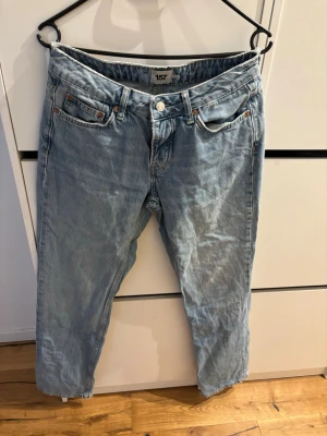 Ljusblå jeans från 157 ICON - Ljusblå jeans från 157 ICON med klassisk femficksdesign och raka ben. Jeansen har en avslappnad passform och är tillverkade i denim med tydliga slitningar för en cool, vintage look. Perfekta för en avslappnad streetstyle.