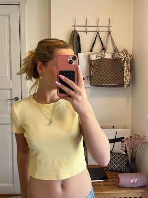 Ljusgul ribbad croppad topp Lindex - Superfin ljusgul croppad topp från Lindex i ribbad bomull. T-shirten har korta ärmar och rund halsringning, perfekt till jeans eller kjol. Enkel och fräsch stil som passar året runt.