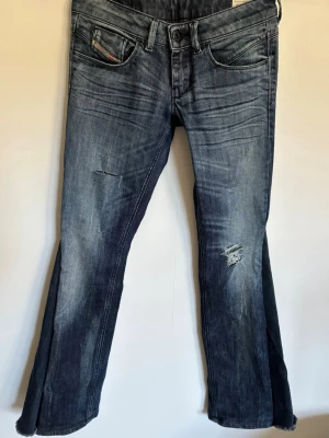 Mörkblå bootcut jeans från Diesel - Jätte snygga jeans!! Med detaljer bak och slitningar fram, Storlek: w26 L32, mått: midjemått rakt över ca 35 cm, Innerbenslängd ca 75 cm. (jeansen passar inte modellen därav bilderna)