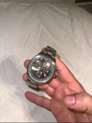 Stilren silverfärgad Champion - Snygg kronografklocka i silver med länkarmband och svart urtavla. Klockan har flera små urtavlor och detaljerade visare, vilket ger en sportig och modern look. Perfekt accessoar för dig som gillar stilrena och klassiska detaljer.