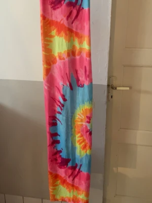 Färgglad långklänning från SHEIN - Långklänning från SHEIN med färgstarkt batikmönster i rosa, blått, gult och orange. Klänningen har en rak passform och är tillverkad i ett mjukt syntetmaterial. Perfekt för dig som vill sticka ut med en unik och lekfull stil.