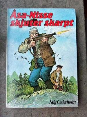 Åsa-Nisse skjuter skarpt bok - Boken "Åsa-Nisse skjuter skarpt" av Stig Cederholm från 1979. ISBN: 91-552-2664-7. Boken innehåller de bästa Åsa-Nisse-historierna. Åsa-Nisse jagar i Knoarhultaskogarna. När gammelgäddan överlistar honom och hustrun, Sarons ros är på krigsstigen – då drar han till skogs med bössan och helst i sällskap med kumpanen Klabbarparn.  Skick ses på bilder!