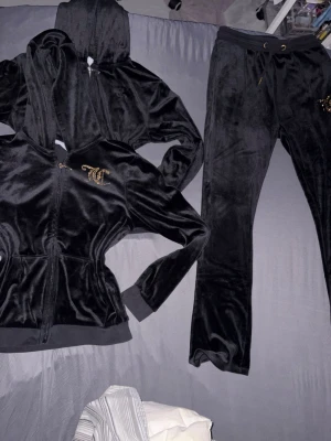 Svart juciy couture  - Jag säljer ett svart sett från juciy couture som knappt används, finns inget fel på kläderna förutom att det kanske försvunnit några (diamanter) från byxorna och tröjan men det är inget som syns. Jag har två svarta koftor som passar med byxorna ( man kan köpa allt tillsammans eller bara en kofta med byxorna) priset nedan är för allt tillsammans.
