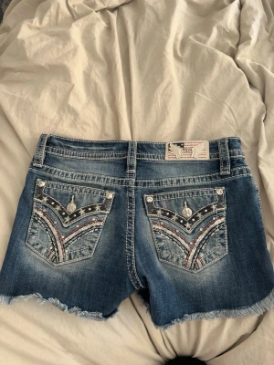 Miss me jeans shorts  - Säljer ett par blå jeansshorts från Miss Me med snygga slitningar och fransig kant. Köpte de i USA så är ganska unika ändå, hör av dig vid intresse!