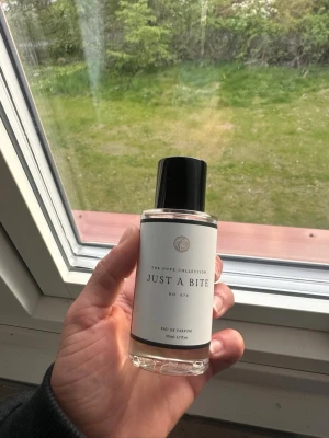 Just A Bite parfym från curiosa - Parfymflaska med svart lock och stilren vit etikett. Doften heter Just A Bite No. 873 och är en Eau de Parfum. Flaskan är genomskinlig och rymmer 50 ml. Perfekt för dig som gillar unika och trendiga dofter.