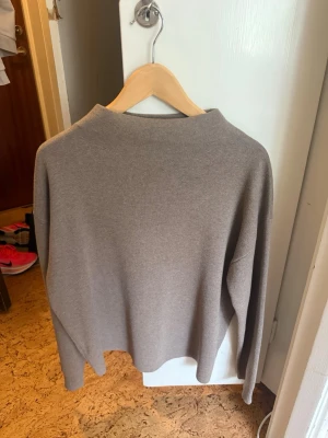 Beige stickad tröja från Åhléns - En stilren beige stickad tröja från Åhléns i storlek M. Tröjan har en rak passform, lång ärm och en enkel, klassisk design med rund halsringning. Perfekt för lager-på-lager och passar till många olika outfits.