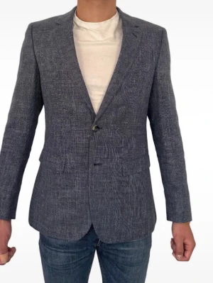 Tommy Hilfiger Kavaj - 46 - Snygg och modern kavaj i en snyggt strukturerad linne- och viskosblandning. Perfekt för både sommarens festligheter och välklädda vardagar! Den har burits väldigt sparsamt och är därför i absolut toppskick (nästintill som ny).  Tack vare materialmixen får du lynnets snygga, luftiga struktur men med mindre skrynklor tack vare polyestern och viskosen.  Exakta mått för perfekt passform: Axelbredd: 44 cm  Armlängd: 64 cm Storlek: 46  Modell på bilden är 177cm och 68kg