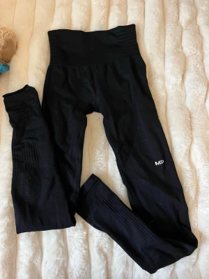Svarta seamless leggings från MP - Snygga svarta seamless leggings från MP med hög midja och diskret logga på benet. Stretchigt material som sitter tajt och bekvämt, perfekt för träning eller chill. Ribbad struktur på benen ger extra stilpoäng.