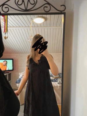 Svart långklänning med volangdetaljer - Svart långklänning med v-ringning och fina volanger upptill. Klänningen har en lös passform och är ärmlös, perfekt för en trendig och avslappnad look.