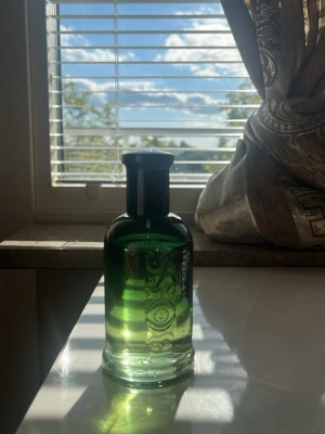 Grön parfymflaska med svart kork - Snygg parfymflaska i glas med en djup grön färg och svart kork. Flaskan har en stilren, rundad form och känns lyxig och modern. Perfekt att ha framme på hyllan eller i badrummet som en snygg detalj.