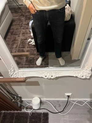 Mörkblå slim fit jeans från Nudie - Snygga mörkblå slim fit jeans från Nudie med klassiska orange sömmar och femficksdesign. Jeansen har en smal passform och är tillverkade i denim med stretch för extra komfort. Perfekta för en stilren och modern look.