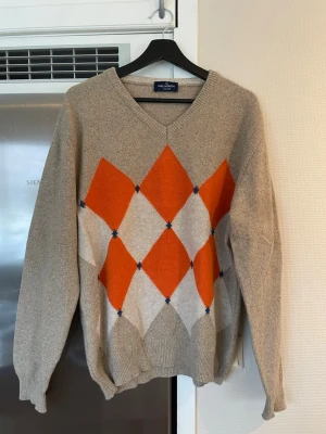Argyle knitted sweater, Malagrida - Stickad tröja i beige från Malagrida med klassiskt argylemönster. V-ringad hals och ribbade muddar. Perfekt för dig som gillar retrostil och vill sticka ut lite extra. 100% soft wool. Regular fit Fits M/L Made in Italy