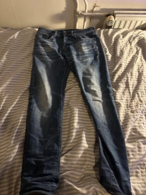 G-Star RAW 3301 Slim jeans blå - Snygga blå jeans från G-Star RAW, modell 3301 klassisk femficksdesign med slitningar och tvättade detaljer för en cool look. Perfekta för dig som gillar stilrena och moderna jeans.                                 Mått: byxlängd från midjan: 122cm                             Innerbyxa: 77 cm                                               Midjan: 37 cm