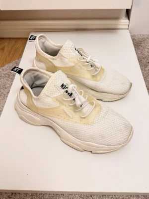 Vita sneakers från Steve Madden - Snygga vita sneakers från Steve Madden med chunky sula och meshdetaljer. Skorna har vita snören, beigea inslag och svart logotyp på hälen. Ovandelen är i textil och syntet, vilket ger en sportig och modern look.
