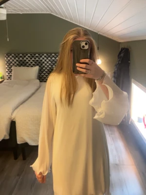 Vit klänning med volangärmar - Säljer en söt vit kortklänning med långa, vida ärmar och volangdetaljer vid ärmslut och nederkant. Klänningen har en lös passform och är perfekt för dig som gillar en enkel men stilren look. Köpt på ginatricot, använd endast 3 tillfällen. 