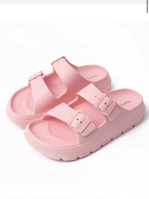 Rosa Happyflops - Säljer ett par ljusrosa sandaler med två breda remmar och justerbara spännen. Sandalerna har en chunky sula och är tillverkade i ett mjukt, flexibelt material som känns bekvämt på foten. Perfekta för en avslappnad och trendig look.