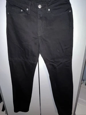 Svarta jeans straight regular fit - Snygga svarta jeans med klassisk femficksdesign och hällor för skärp. Jeansen har en smal passform och stängs med knapp och dragkedja. Perfekta till en cool streetstyle-look. Aldrig använda. Originalen pris 449kr. 29/32 CN/175/74A