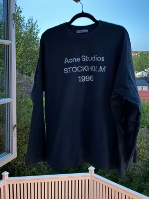 Acne studios tröja  - Acne Studios långärmade tröja i marinblått med ikoniskt Stockholm 1996-tryck. Minimalistisk design med oversized fit och premium känsla — perfekt för en clean streetwear-look. 🖤