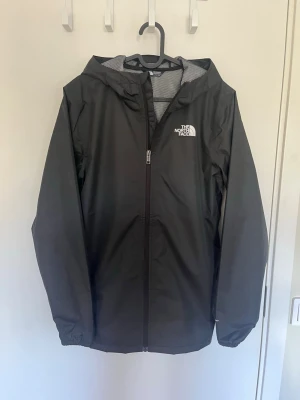 Svart regnjacka från The North Face - Jackan är i perfekt skick och aldrig använd. Ny pris=1200-1400kr✅ Jackan är i storleken XXL i junior storlek vilket jag skulle säga motsvarar S/M i vuxenstorlek. Priset går att diskutera!✅