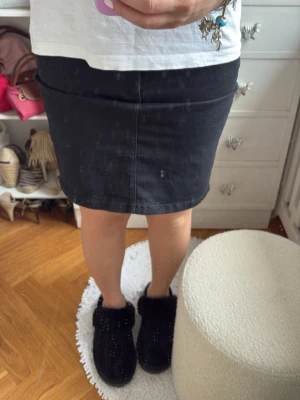 Svart pennkjol i bomull - Svart, figurnära pennkjol i bomull med klassisk midja och knapp framtill. Enkel och stilren design som passar till många olika looks. Perfekt för dig som gillar en clean och tidlös stil.