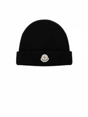 Svart Moncler mössa  - Svart ribbstickad mössa från Moncler med uppvikt kant och klassisk Moncler-logga framtill. Tillverkad i mjuk ull som håller dig varm och snygg under kalla dagar. Perfekt accessoar för en stilren look.