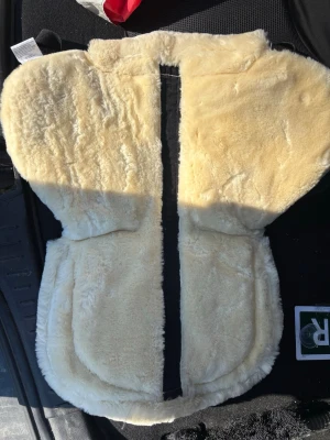 Padd till sadel Fairfield - Mjuk och skön padd till sadel från Fairfield. Ena sidan är naturfärgad och andra sidan är svart, quiltad textil med kardborreband för enkel fastsättning. Perfekt för extra komfort till hästen. Sällan använd så nyskick. Storlek full. Modell PAD CORRIDALE CORRECTION.