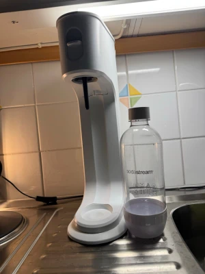 Vit kolsyremaskin från Aqvia - Säljer en stilren vit kolsyremaskin från Aqvia. Maskinen har en modern design i plast och levereras med en tillhörande flaska. Perfekt för att göra bubbelvatten hemma på nolltid. Obs! Säljes utan kolsyrepatron och flaska! Flaskan står bredvid bara så man ska få ett hum om hur stor den är!