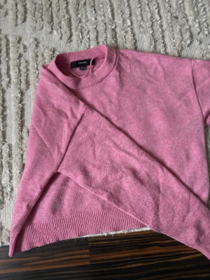 Rosa stickad tröja från Vero Moda - Säljer en söt rosa stickad tröja från Vero Moda. Tröjan har rund halsringning, långa ärmar och ribbade muddar vid ärmslut och nederkant. Perfekt för att addera lite färg till din garderob!