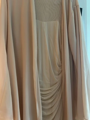 Beige omlottklänning med drapering (tillbehör Abaya) - Anständig klänning med Abaya. Lång och täckande passar för kvinnor som vill täcka sin kropp men ändå ha figuren. 