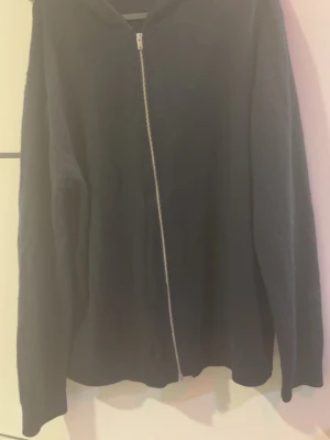 Cashmere hoodie Massimo Dutti - Snygg svart hoodie från Massimo Dutti med dragkedja framtill och huva. Tillverkad i mjukt material som känns skönt mot huden. Perfekt för dig som gillar en clean och enkel stil. Passar till det mesta och är lätt att matcha.