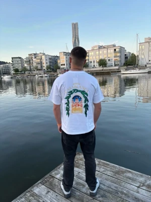 Vit Casablanca t-shirt med tryck - Vit t-shirt från Casablanca med färgglatt tryck på ryggen och mindre tryck på bröstet. Klassisk passform med korta ärmar och rund hals. Perfekt för dig som gillar stilrena plagg med en twist. Tillverkad i mjuk bomull.