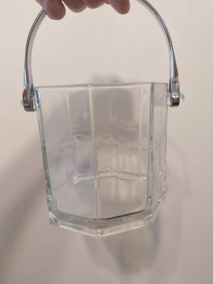 Sexkantad ishink i glas med handtag - Snygg sexkantig ishink i klart glas med dekorativt mönster runt om och ett robust handtag i metall. Perfekt till festen eller hemmabaren för att hålla isen kall och stilren. Enkel att bära tack vare det praktiska handtaget.