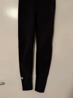 Svarta sportleggings från 157 - Svarta leggings från 157 med smal passform och stretchigt material. Diskret logga vid vristen och bekväm midja. Perfekta för en avslappnad och sportig stil.