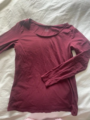 Mörkröd långärmad topp - En enkel och stilren vinröd långärmad topp med rund halsringning. Tillverkad i mjukt bomullsmaterial, perfekt för lager på lager eller att bära som den är. Passar till det mesta och är lätt att matcha med olika stilar.
