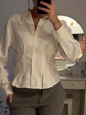 Vit figursydd skjorta med knappar - Snygg vit skjorta med figursydd passform och klassisk krage. Skjortan har långa ärmar och knäppning framtill. Perfekt för en stilren look och enkel att matcha med olika outfits.