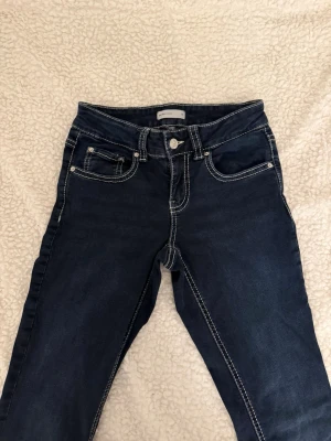Mörkblå jeans från Perfect Jeans - Snygga mörkblå jeans från Perfect Jeans med kontrasterande vita sömmar och klassisk femficksmodell. Jeansen har normal midja och raka ben, tillverkade i ett mjukt denimtyg som sitter skönt hela dagen.