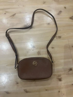 Brun axelväska från Michael Kors - Superfin Micheal Kors väska i brunt läder köpt i USA med prislapp på för 198$ ca. 2000kr och har aldrig använts!