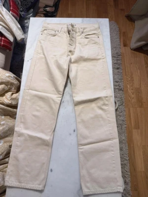 Beiga raka jeans från Junkyard - Snygga beiga jeans från Junkyard, modell Nevermind Jeans. De har rak passform, klassisk femficksdesign och är tillverkade i ett kraftigare bomullstyg. Perfekta för en clean och avslappnad stil.