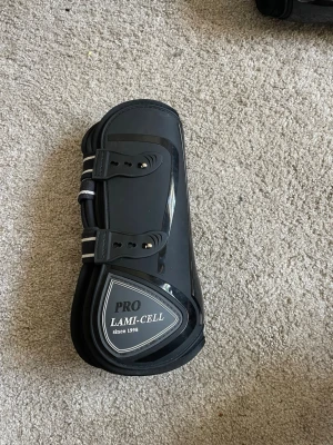 Svarta benskydd Lami-Cell Pro - Säljer två likadana benskydd från Lami-Cell, dessa har mindre slitning och om man kollar min profil på dom andra så har dom mer slitning. Dessa är använda 1 gång. Det är ett par svarta benskydd från Lami-Cell Pro, perfekta för större häst. Ordinarie pris 750kr. Märket och modellen står tydligt på skyddet. Snygg och funktionell design för ridning. Skriv gärna om du undrar något osv!