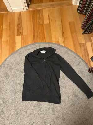 Mörkgrå hoodie från Selected Homme - Snygg mörkgrå hoodie från Selected Homme med dragkedja framtill och klassisk huva. Tillverkad i mjukt material som känns skönt mot huden. Perfekt för en avslappnad och stilren look.