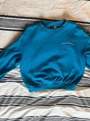 Blå hoodie från H&M - En fin blå tjocktröja från H&M med texten 'INHALE & EXHALE' broderad på bröstet. Gjort av 60% bomull & 40% polyester. Använd fåtal gånger men ingen skada eller något som egentligen märks, hängt i gaderoben på en galje annars.