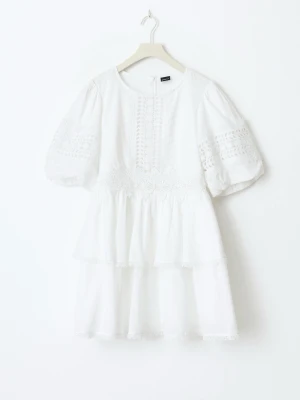 Studentklänning - Superfin vit kortklänning från ginatricot med puffärmar och spetsdetaljer på både ärmar och bröst. Klänningen har volang och omlottliknande kjol, samt broderade inslag. Perfekt för sommarens alla tillfällen. Nypris 799kr