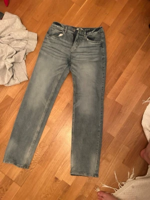 Blå raka jeans från Lindex - Snygga blå jeans från Lindex i rak modell med klassisk femficksdesign. Jeansen har en ljus tvätt och är tillverkade i bomull. Perfekta för en avslappnad och trendig stil.