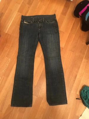 Diesel bootcut jeans low waist - Snygga mörkblå bootcut jeans med klassisk femficksdesign och kontrastsömmar. Jeansen har en rak passform över låren och lätt utsvängda ben. Perfekta till sneakers eller boots och passar till många olika stilar.